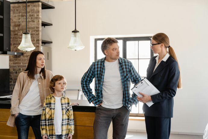 Family with child talks to real estate agent in modern kitchen during home showing.